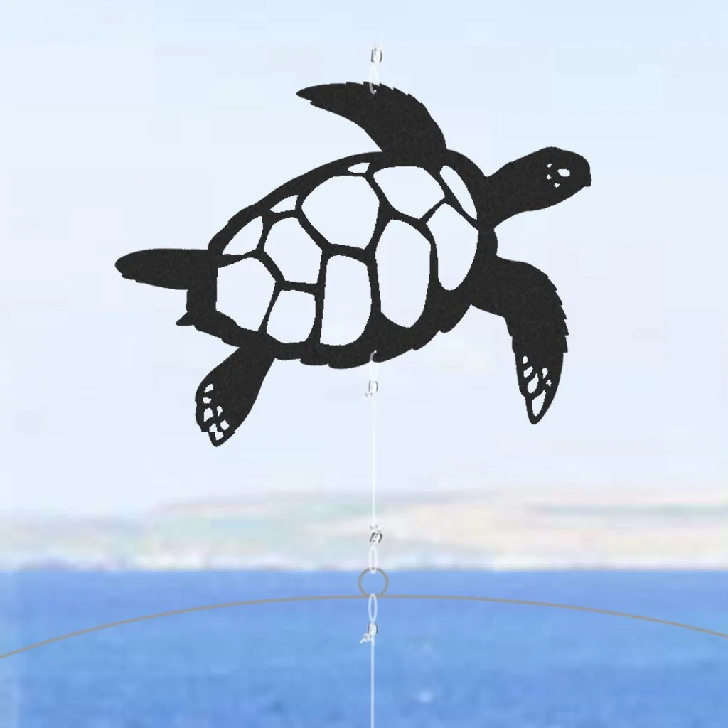 Silueta negra de una tortuga marina nadando, pieza superior del móvil decorativo de océano y buzo con fondo de mar desenfocado.